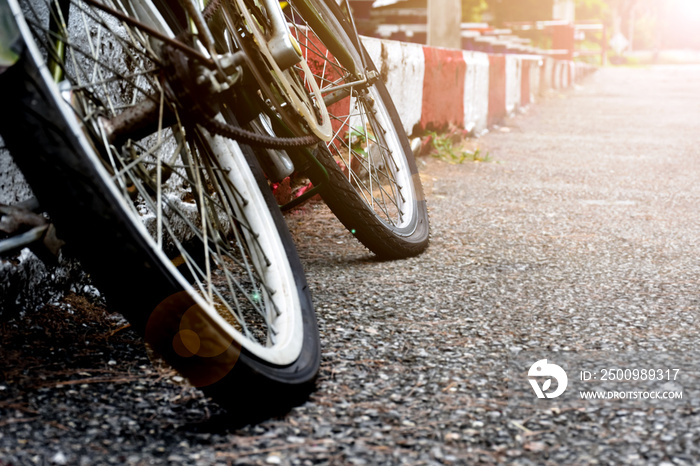 Bike flat tires which parked on red-white line beside the road in the public park, soft and selective focus on tire.