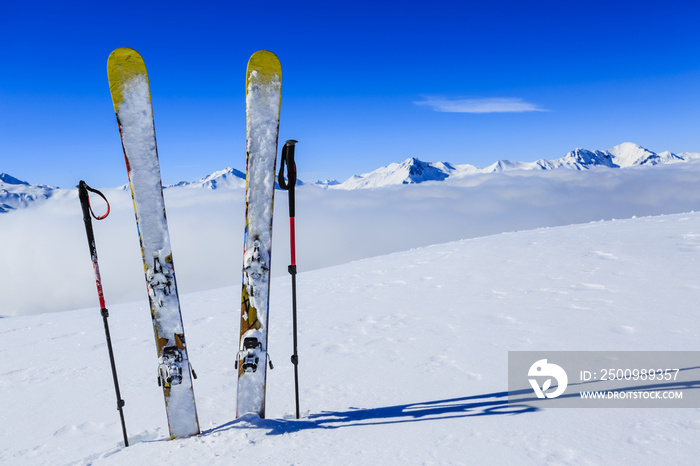 Ski in winter season, mountains and ski touring equipments on the top in sunny day in France, Alps above the clouds.