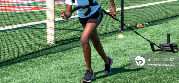 Runner pulling a sled with weights on a green turf field