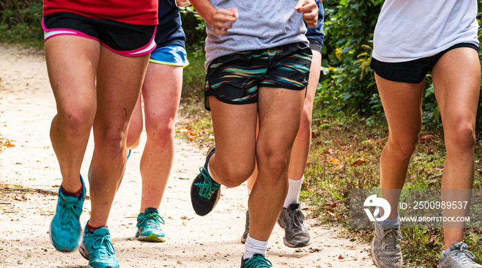 Legs of girls running on a dirt path in a park