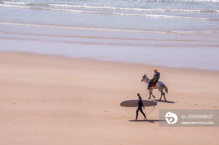 Paisaje con surfista y jinete en la costa de Taghazout en el sur de Marruecos