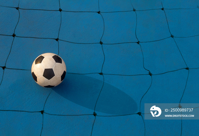 Football on floor with goal net on blue background