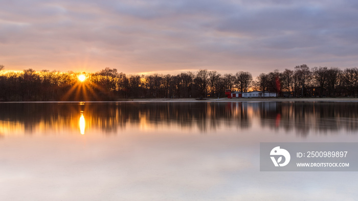 Evening mood with reflections and a sun star at the Silbersee, Germany, Lower Saxony, Hanover, Langenhagen