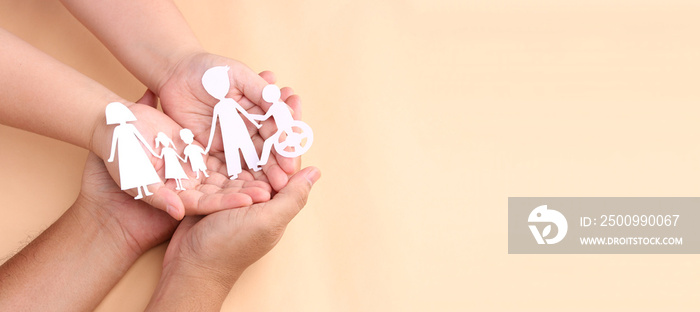 hands holding paper Cutout of different family members being together.