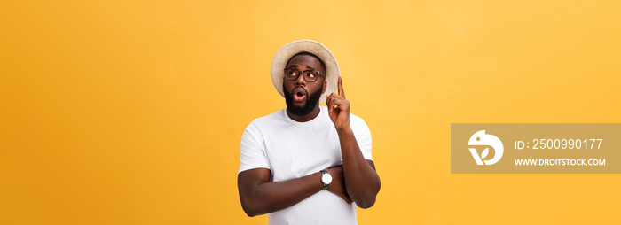 Portrait of a pensive afro american man in glasses looking up at copyspace isolated on a yellow background