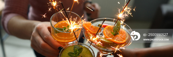 Goup of people holding cocktails in their hands with sparklers