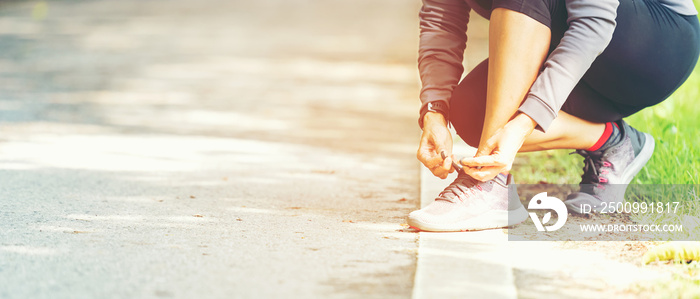 Running woman tying laces of running shoes