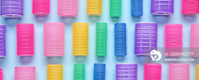 Set of hair curlers on blue background, top view