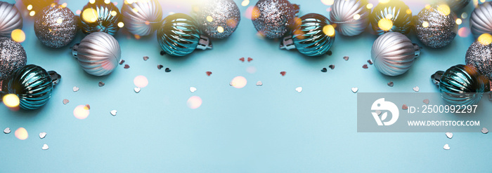 Christmas baubles on blue background. Frame border. Christmas New Year composition background blue grey silver colored. Christmas lights. Minimal concept.