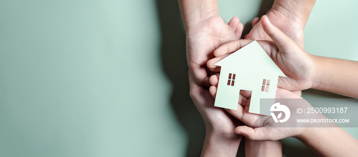 Hands holding wooden house, family home, homeless housing, mortgage crisis and home protecting insurance, international day of families, foster home care, family day care, stay home concept