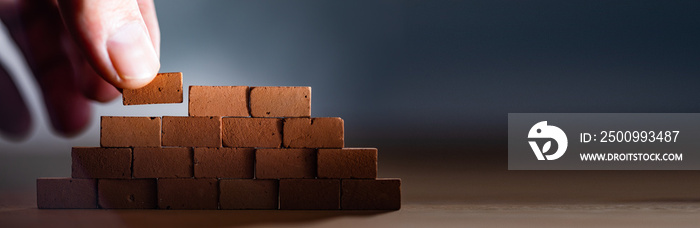 Hand placing wooden blocks stacked collapse prevention