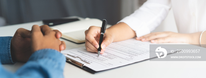 financial investor advisory.  Close up hand pointing at contract and document while sitting together with young couple at the desk in office