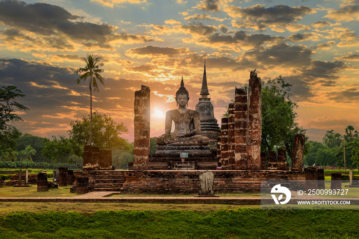 Buddha statue and pagoda Wat Mahathat temple with dramatic syk sunset, Sukhothai Historical Park, Thailand