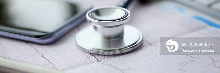 Medical stethoscope head and silver pen lying on cardiogram chart closeup. Cardio therapeutist pulse graph cardiac physical heart rate measure arrhythmia 911 er and resuscitation concept