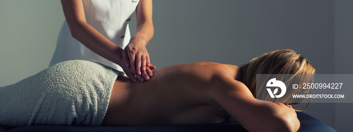 Woman getting back massage therapy in health spa while lying on massage table