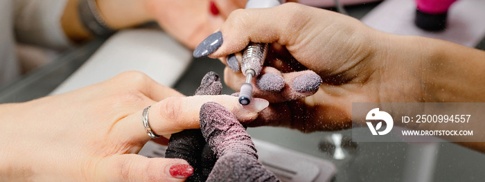 Horizontal banner close up unrecognizable  woman hands. Manicurist removing gel from client’s nails with milling cutter. Beauty, professional, process concept.