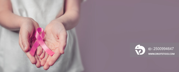 World cancer day. Small hands holding ribbon symbol. Cancer awareness month. Breast cancer.