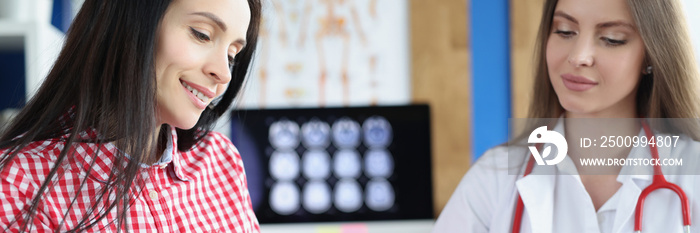 Smiling female patient signs medical form at clinic meeting with doctor