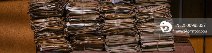 old newspaper piles ready to be recycled, environment, reusable material, yellowed, brown and brittle. banner