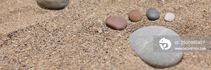 Feet are made of stones on beach sand.