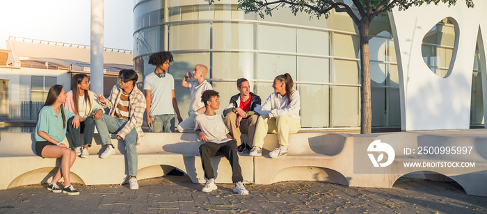 Big group of happy teenage friends talking in a bench in the street of the student campus banner with copy space.