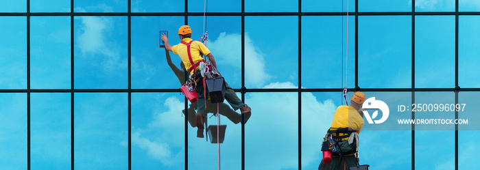 Two workers washing windows of the modern building