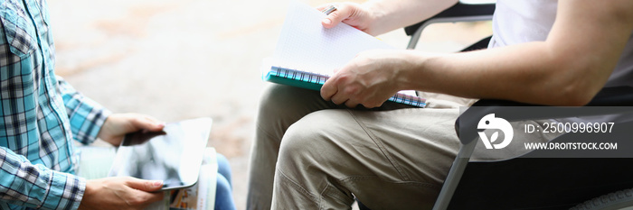 Man in wheelchair and woman holding digital tablet and textbooks closeup