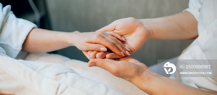 Side view photo of a caucasian woman sitting on the spa couch in a wellness center having a palm massage procedure