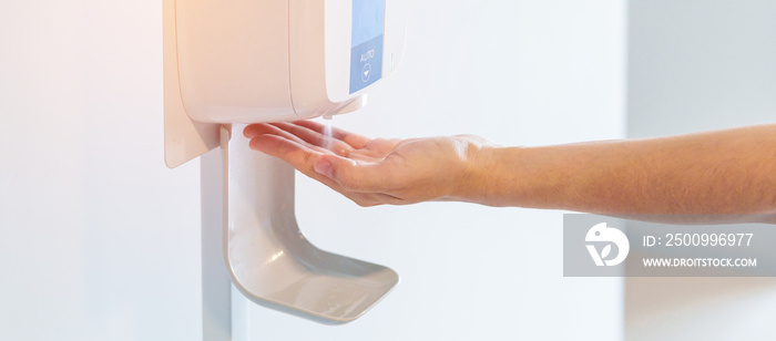 hand spray by automatic sanitizer dispenser in office or apartment. Contactless and Personal hygiene concept