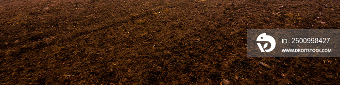 Plowed agricultural field, tractor tracks, soil texture close-up. Rural scene. Panoramic landscape. Farm and food industry, alternative energy and production, environmental conservation theme