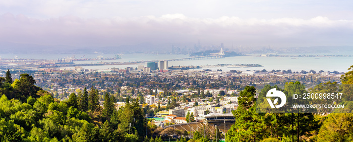 Panoramic view of Berkeley; San Francisco Bay shoreline with Port of Oakland, Yerba Buena Island, Treasure Island, the Bay bridge and the San Francisco skyline visible in the background; California