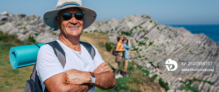 Happy senior man who practices trekking looking at camera