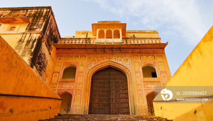 Breathtaking panoramic scenic view of Amber Fort and Palace during morning hours in yellow and orange light near Jaipur in Rajasthan in India