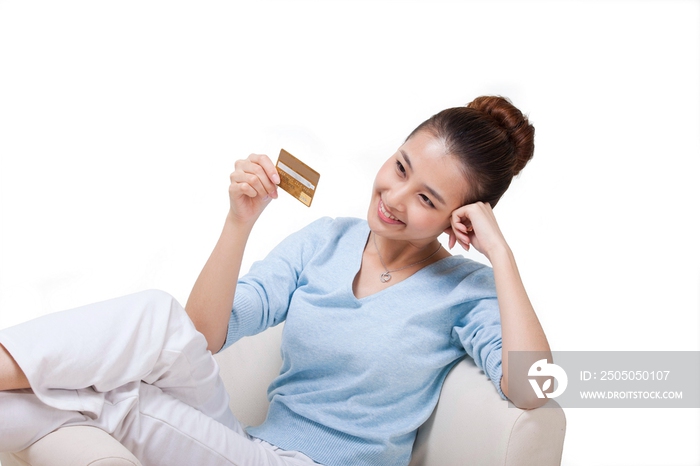 年轻女人坐在沙发上拿着信用卡