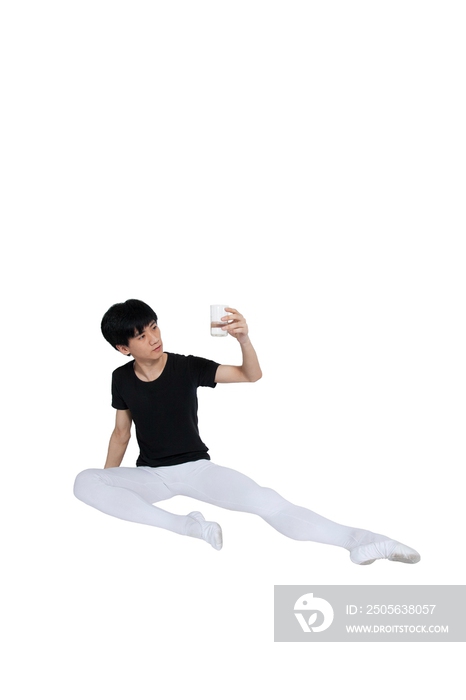 棚拍年轻的芭蕾舞男演员坐在地上喝水休息