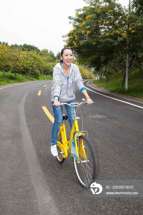 一个年轻女大学生在校园里骑车