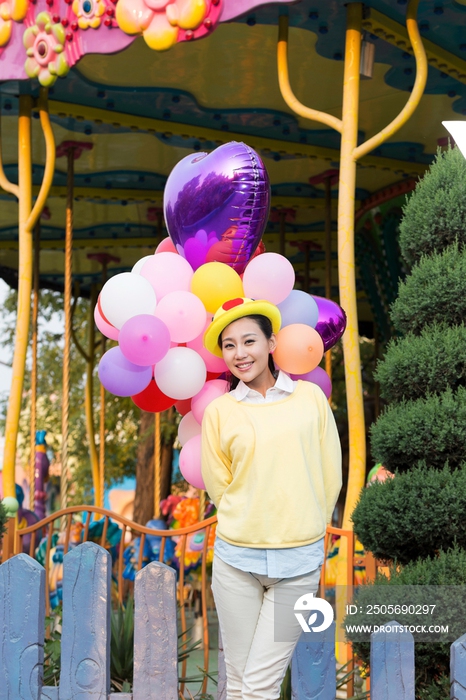 年轻女人牵着气球在游乐园
