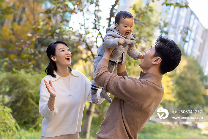 年轻父母在公园陪宝宝玩耍