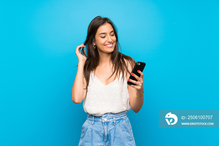 Young woman over isolated blue background making a selfie