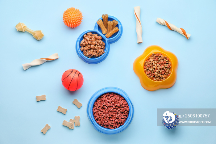 Bowls with pet food and toys on color background