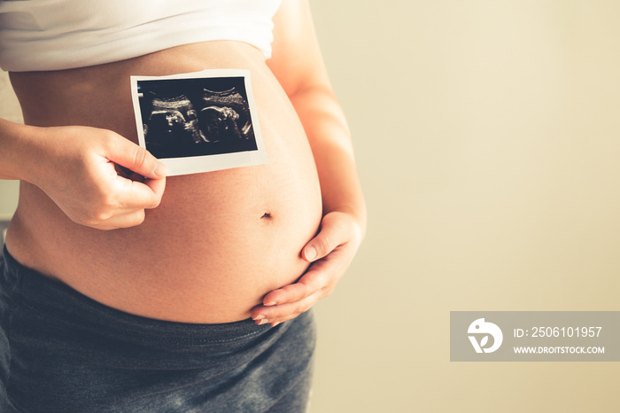 Pregnant woman feeling happy at home while taking care of her child. The young expecting mother hold