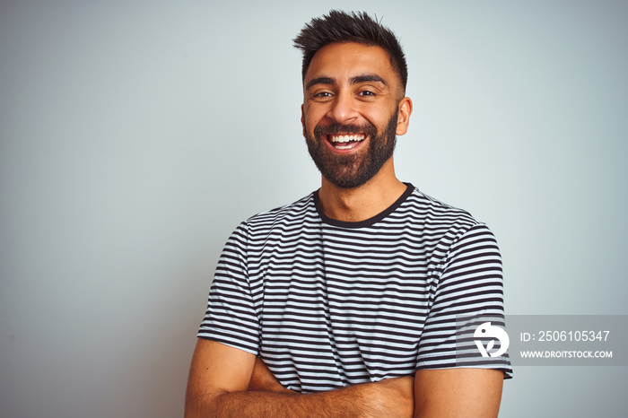 Young indian man wearing black striped t-shirt standing over isolated white background happy face sm