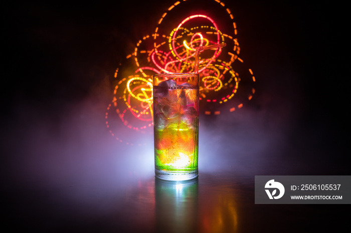 Cocktail glass splashing on dark toned smoky background or colorful cocktail in glass. Party club en