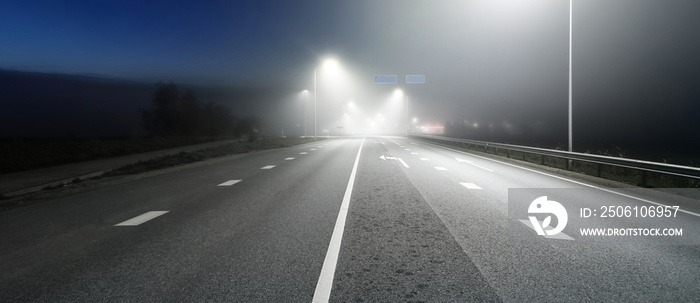 Panoramic view of the illuminated new highway in a fog at night, street lights close-up. Moonlight. 