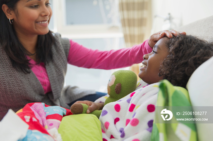 Mother feeling daughters forehead for temperature