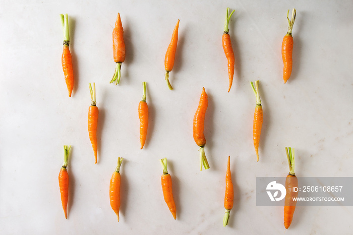 Young mini carrot in row over white marble background. Flat lay, space. Cooking concept, food backgr