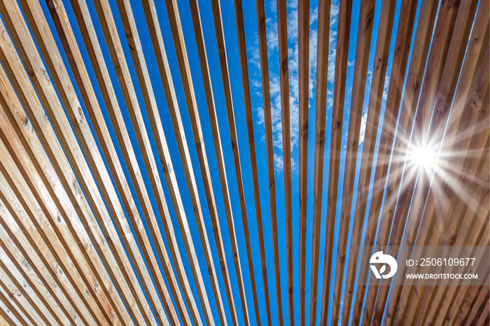 soleil à travers lames de toit d’une pergola