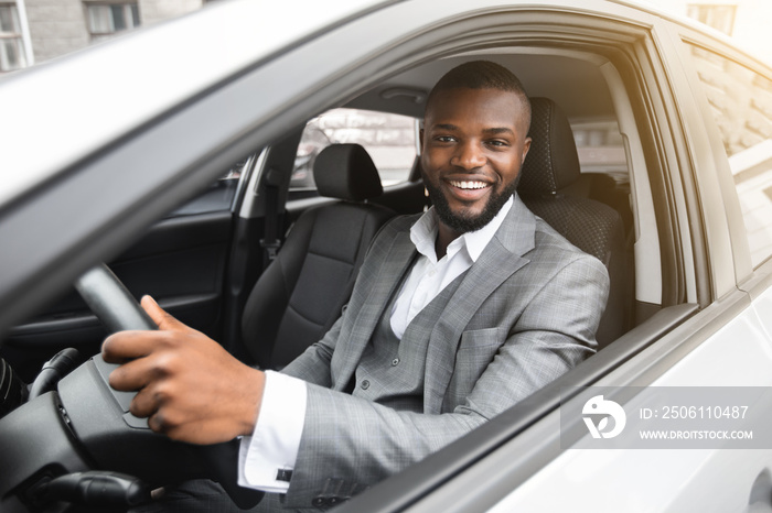 Handsome smiling black businessman driving luxury car