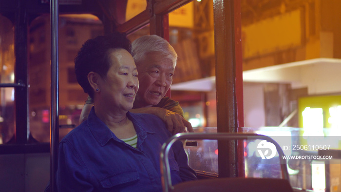 亚洲老年夫妇夜间乘坐香港城市电车畅游