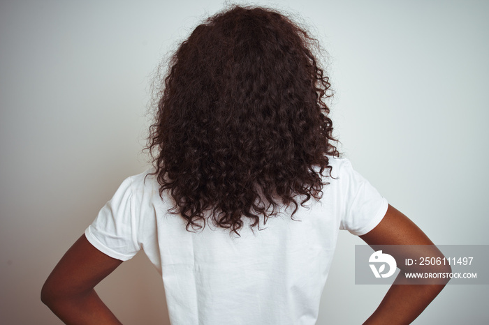 Young african american woman wearing t-shirt standing over isolated white background standing backwa